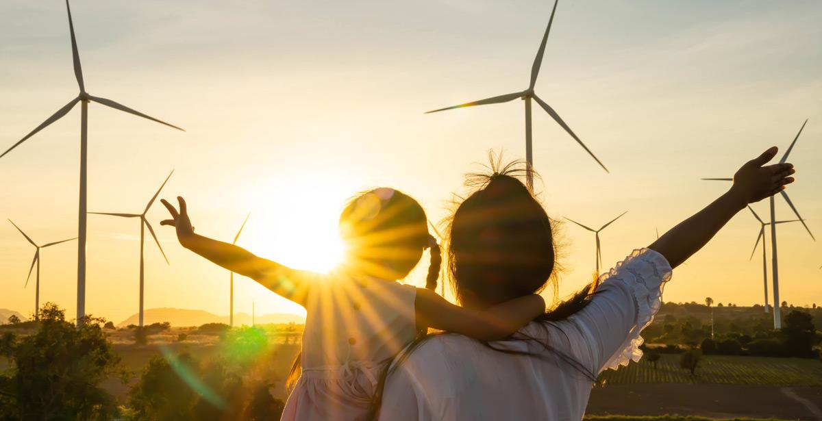 Mamma e figlia al tramonto osservano pale eoliche - Foto di Kampan da Adobe Stock