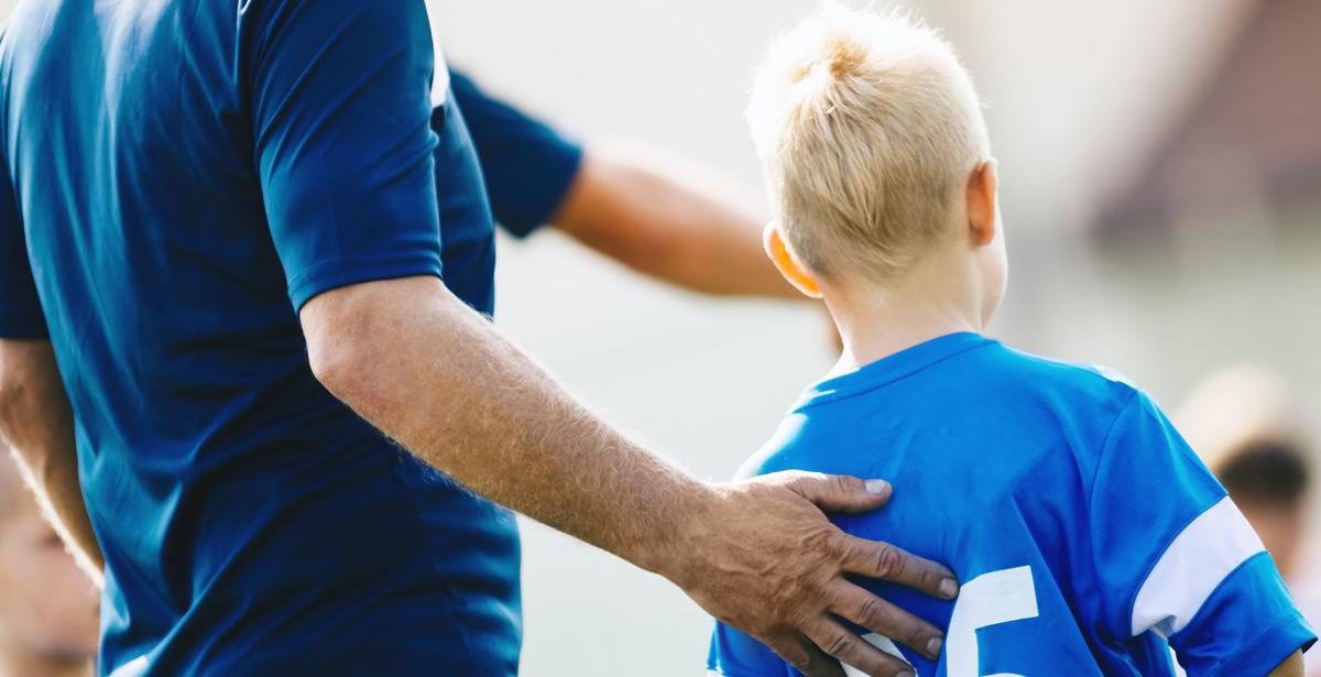 Allenatore supporta piccolo calciatore - Foto di matimix da Adobe Stock