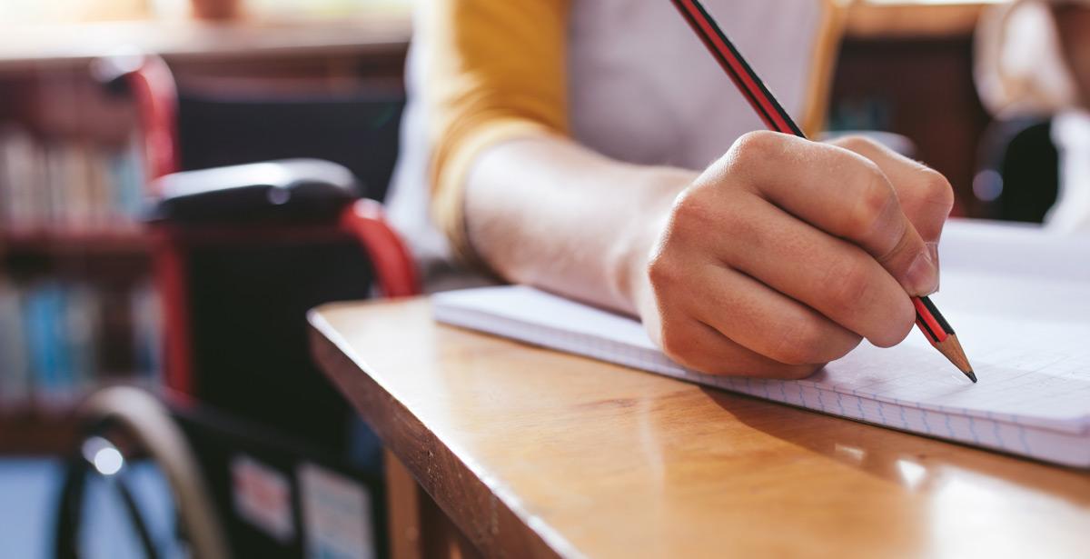 Alunno disabile scrive su quaderno - Foto di Jacob Lund da Adobe Stock