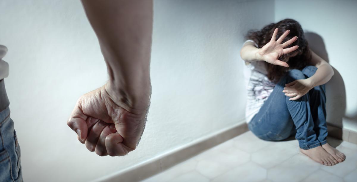 Uomo di spalle minaccia donna accovacciata in un angolo - Foto di Romolo Tavani da Adobe Stock