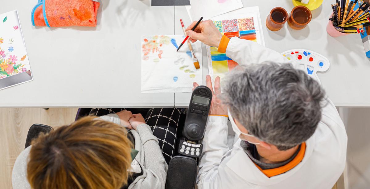 Insegnante di disegno con una bambina su sedia a rotelle - Foto di Mikel Allica da Adobe Stock