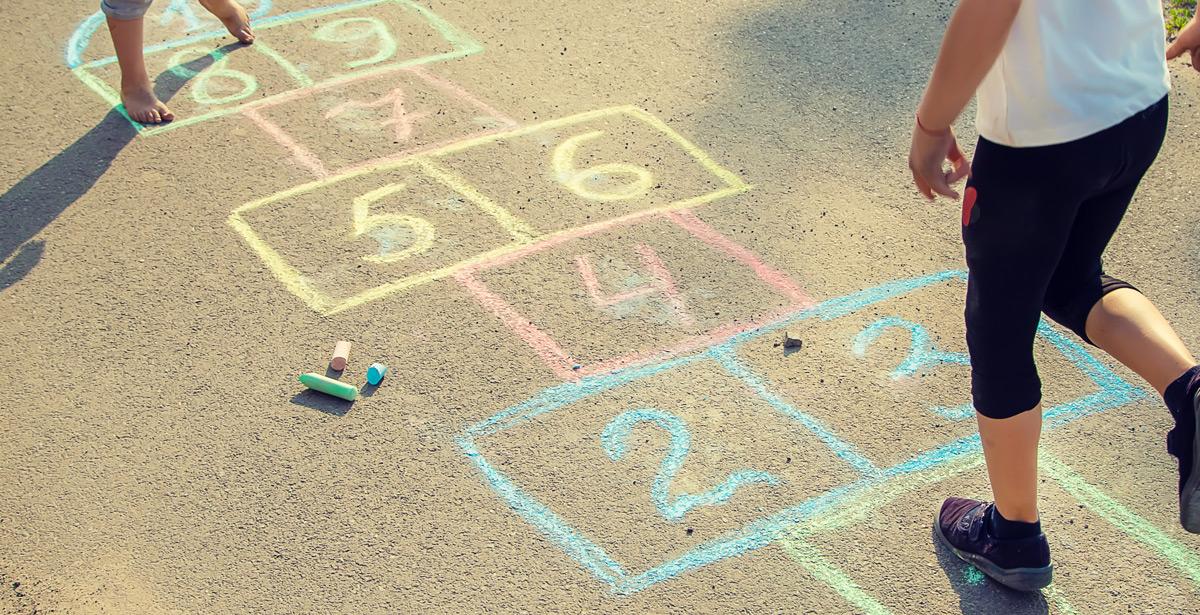 Due bambini giocano a campana sulla strada - Foto di yanadjan da Adobe Stock