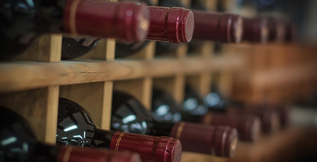 Bottiglie di vino rosso in scaffali di legno - Foto di M-Production da Adobe Stock