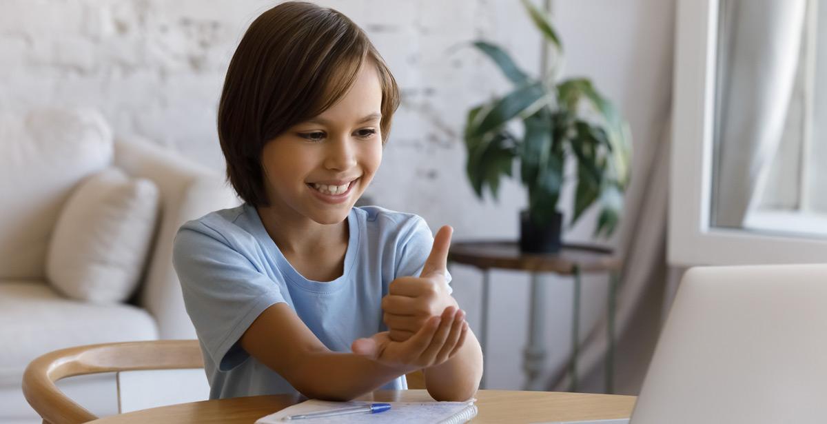 Bambino non udente usa il linguaggio dei segni durante una lezione a distanza - Foto di fizkes da Adobe Stock