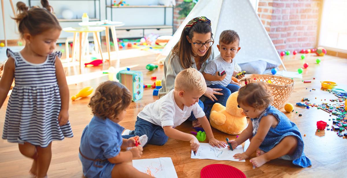 Giovane maestra insegna ai piccoli a disegnare con carta e matite colorate - Foto di Krakenimages.com da Adobe Stock