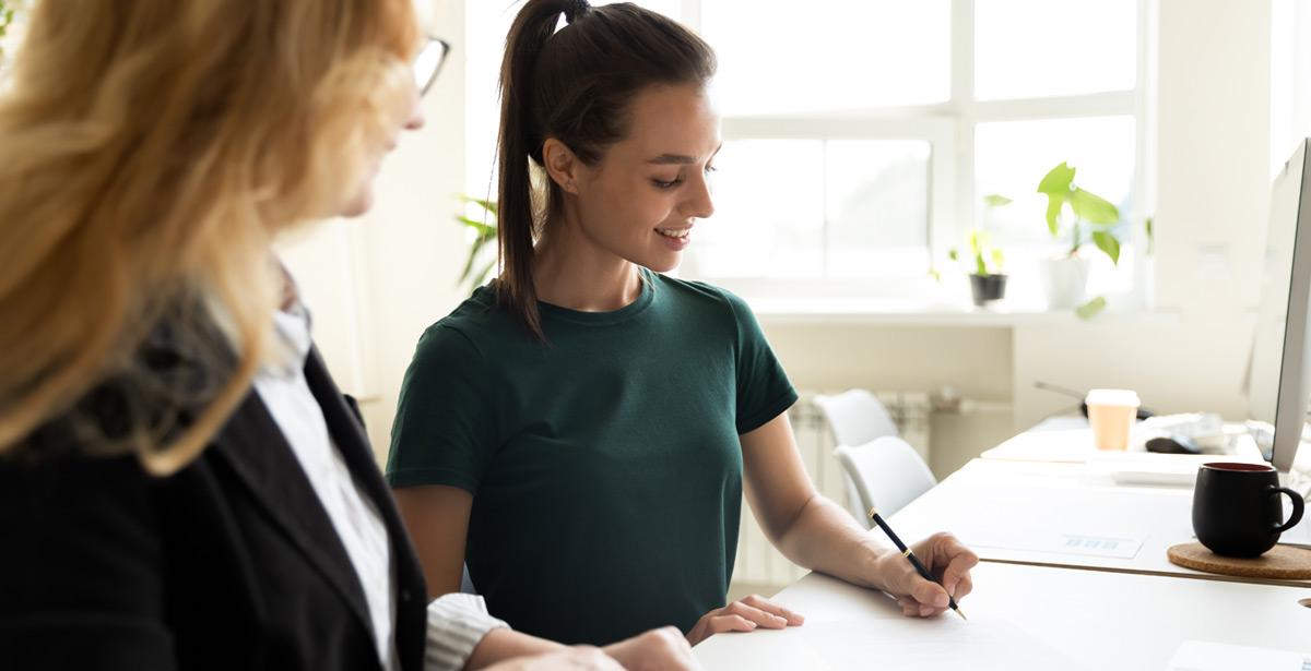 Tirocinante con supervisore lavorano alla scrivania - Foto di fizkes da Adobe Stock