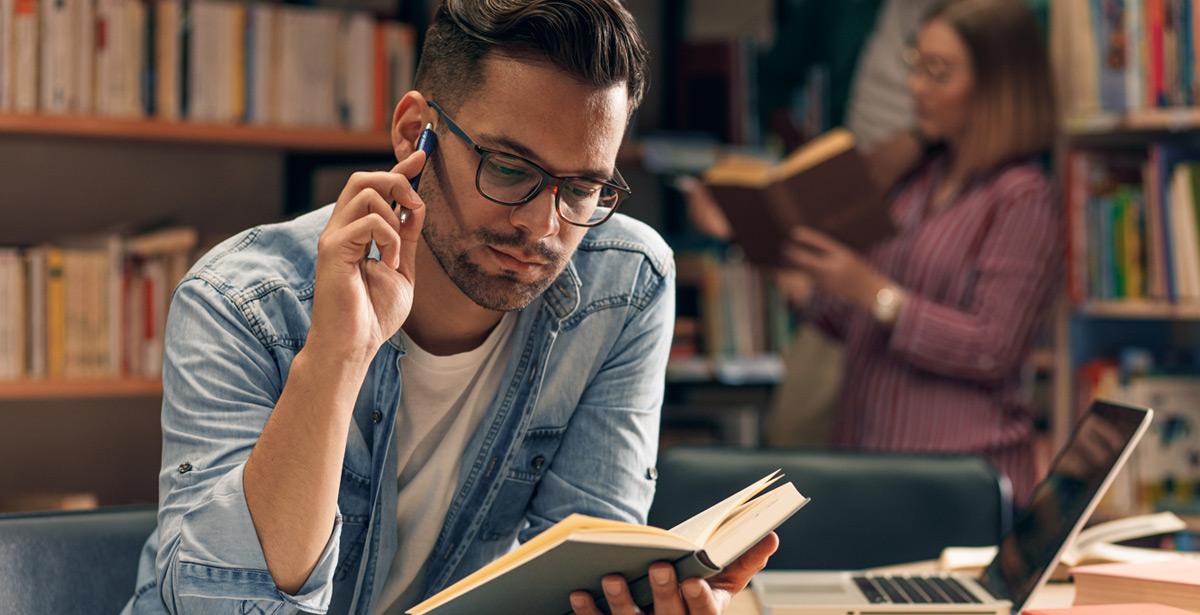 Studente legge un libro in biblioteca - Foto di Zoran Zeremski da Adobe Stock