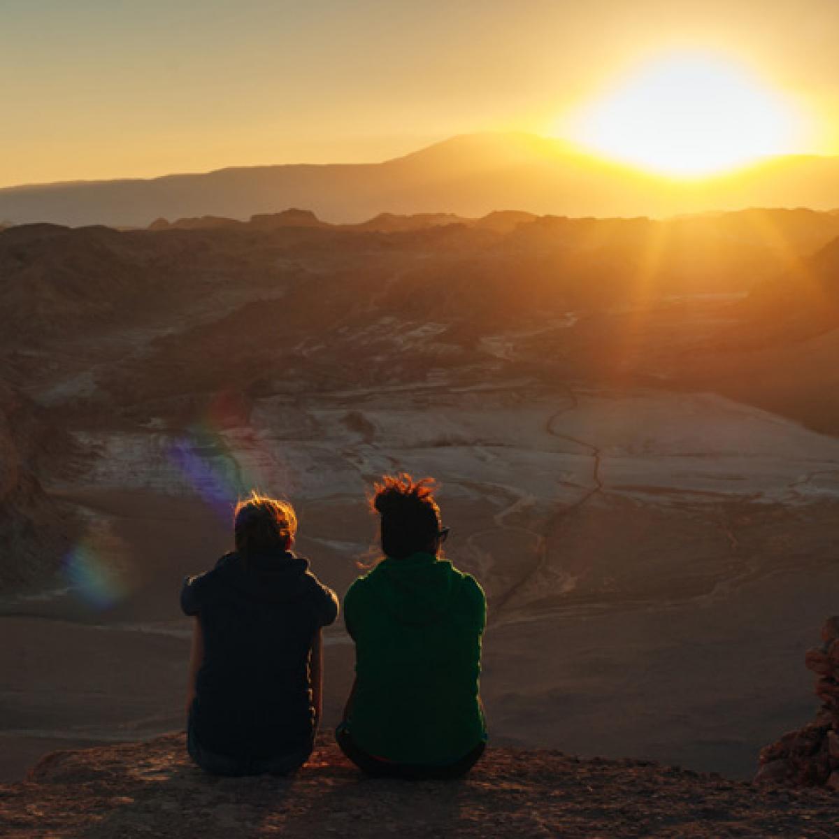 Due donne sedute osservano l'alba - Foto di IBRESTER da Adobe Stock