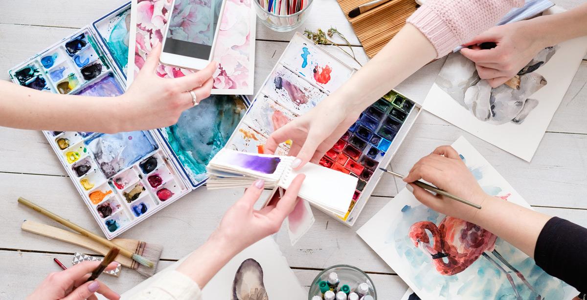 Mani femminili lavorano con colori su un tavolo - Foto di golubovy da Adobe Stock