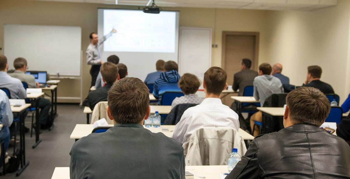 Persone sedute in aula durante un corso con docente alla lavagna elettronica - Foto di elen31 da Adobe Stock