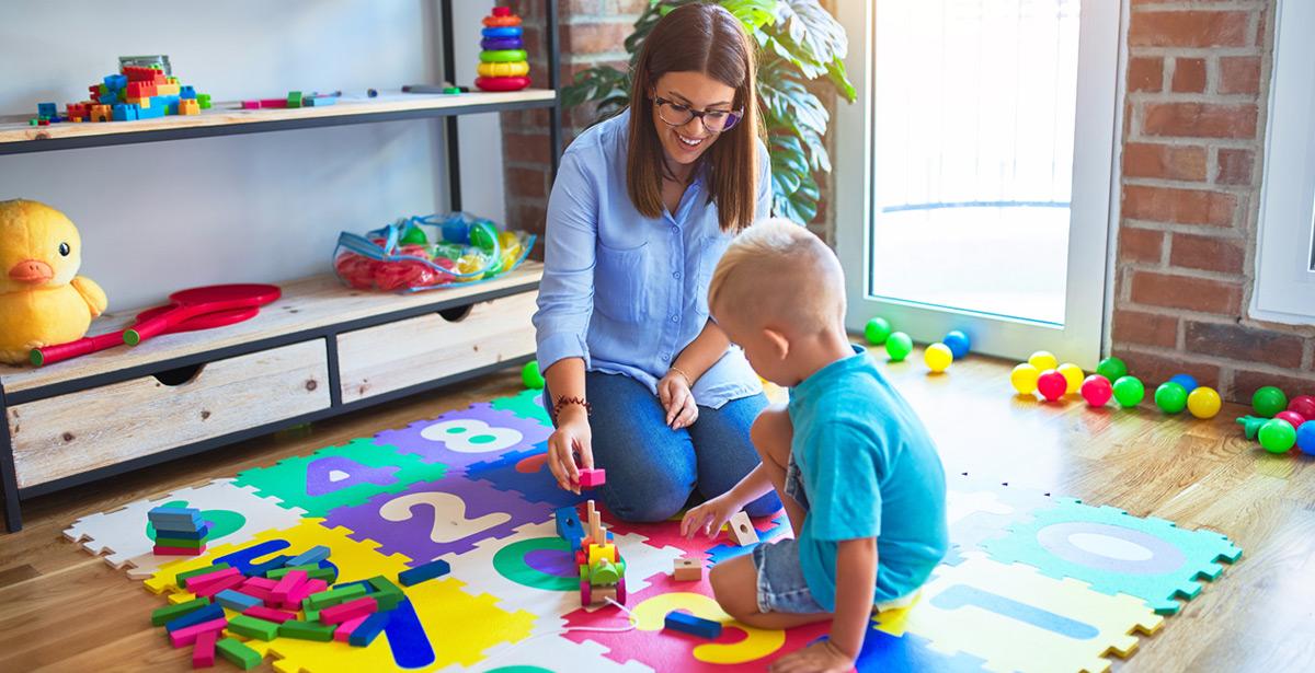 Educatrice gioca con un bambino in classe - Foto di Krakenimages.com da Adobe Stock