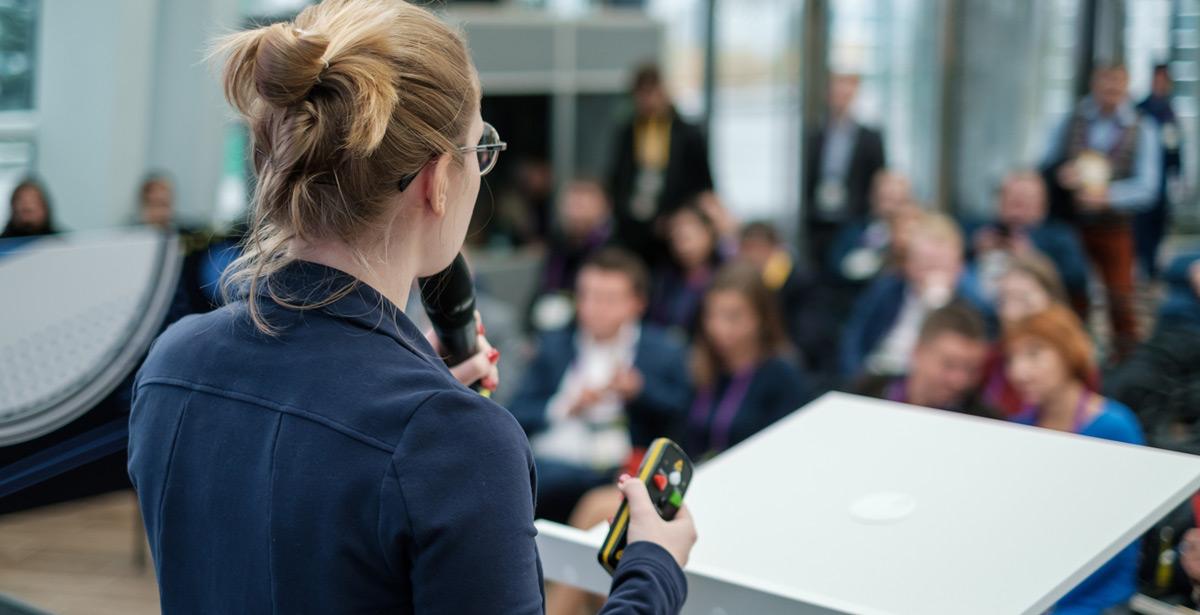 Istruttrice parla ad una platea di studenti durante giornata di orientamento - Foto di Anton Gvozdikov da Adobe Stock